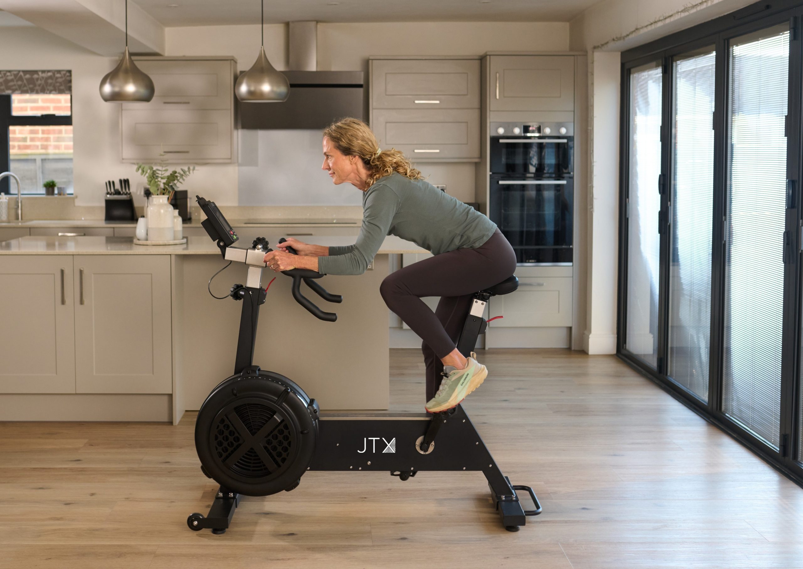 Women using the new JTX Ignite AirX Rider Exercise bike in the kitchen